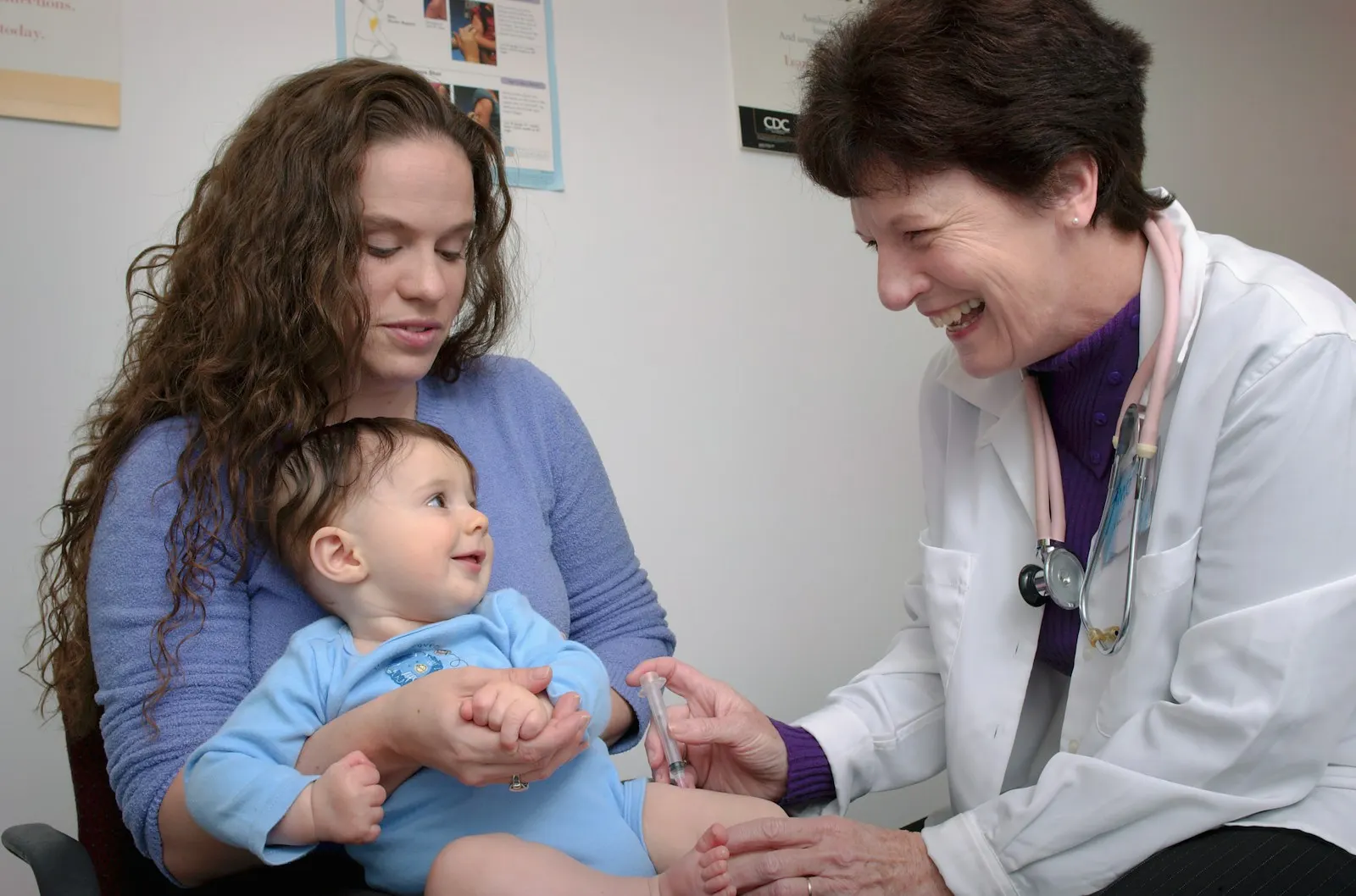 A doctor giving a baby a vaccination while the mother holds the baby