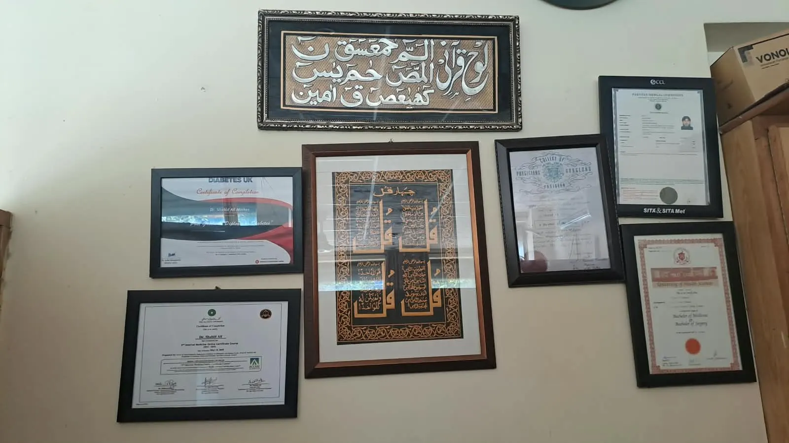 Framed certificates and calligraphy on the wall at Minhas Clinic