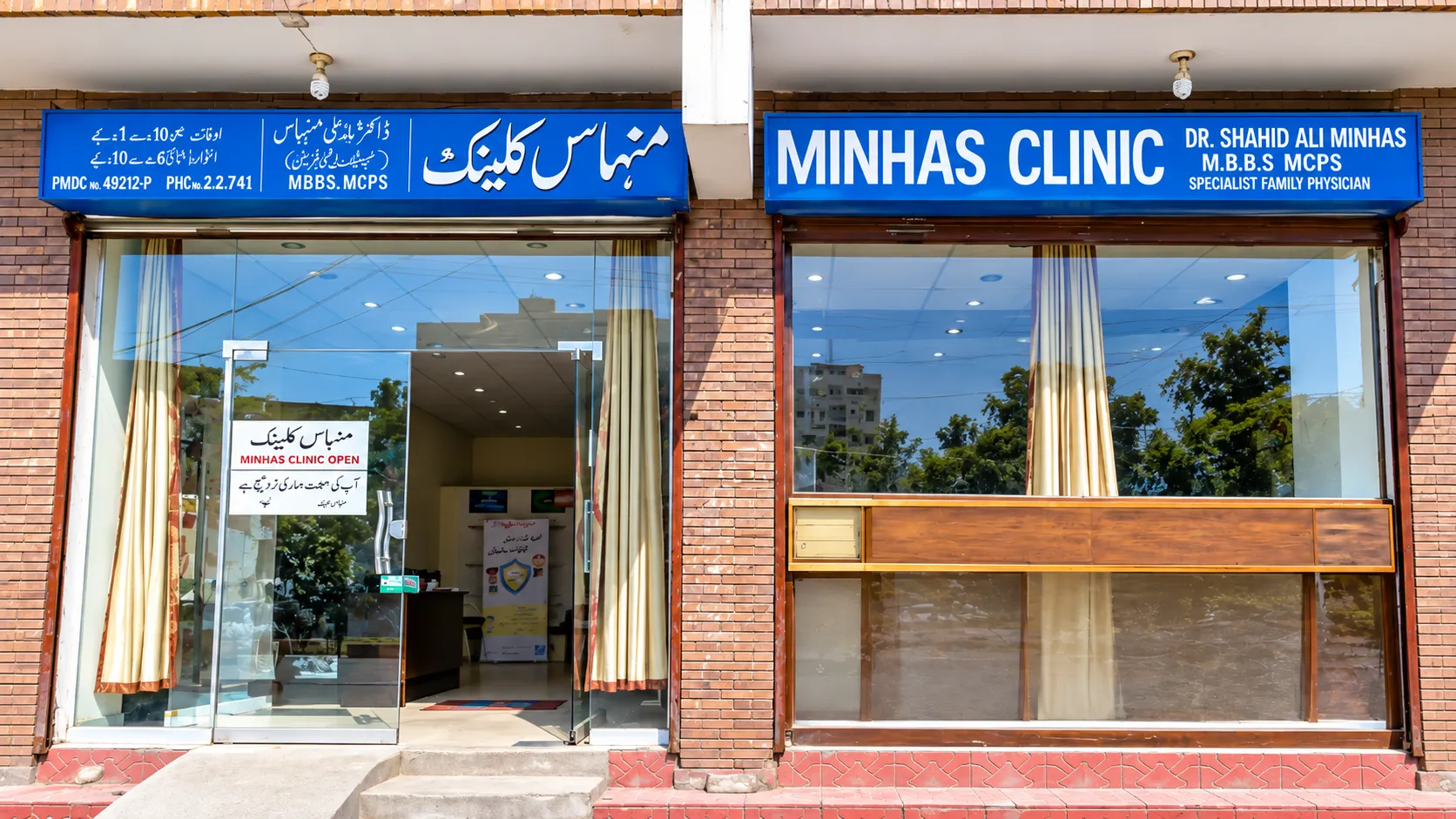 Front of Minhas Clinic on Umer Farooq Road, Township, with blue signboards in English and Urdu