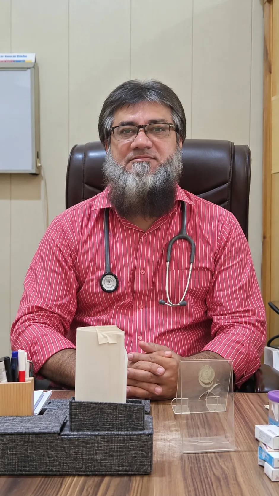 Dr Shahid Ali Minhas, Specialist Family Physician, at his desk in Minhas Clinic