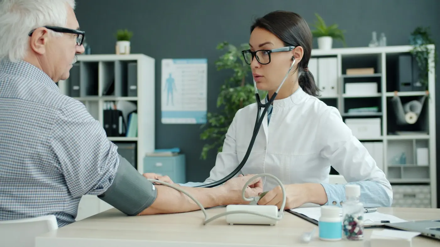 A doctor checking an older patient's blood pressure